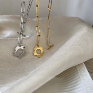 Detail of OT toggle closure and hollow flower pendant on gold and silver chain bracelet