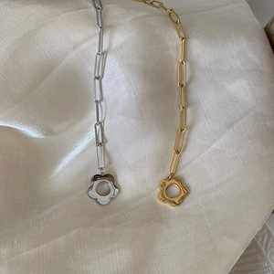 Detail view of gold and silver hollow flower pendants on stylish paperclip link chains