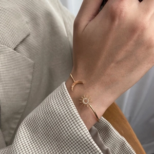 Elegant gold celestial bangle featuring sparkling star and moon motifs on a thin open band