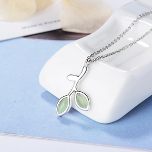 Macro detail of leaf-shaped silver necklace featuring two light green cat-eye stones