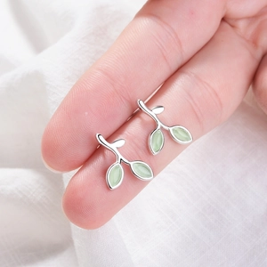 Macro shot of 925 sterling silver leaf earrings with light green opals on fingertips