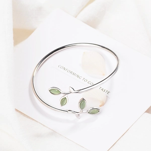 Detail of silver leaf bracelet with soft green opal-like stones on white fabric