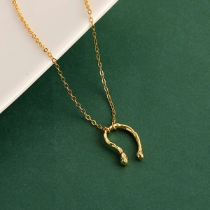 Detail of gold U-shaped horseshoe pendant with textured hammered finish on a fine chain