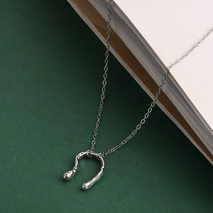 Macro detail of silver horseshoe pendant with irregular hammered texture on paper