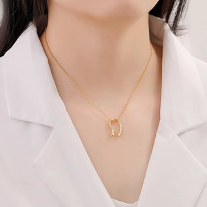 Minimalist gold U-shaped horseshoe pendant necklace on a model wearing a white shirt