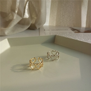Close-up of gold and silver hollow heart-shaped open rings on a hexagonal tray