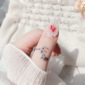 Close-up of adjustable letter E silver ring with white zircon stones on a woman's finger