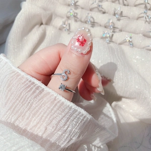 Close-up of adjustable silver ring featuring a letter S with crystal and a round solitaire