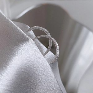 Sparkling silver hoop earrings with frosted texture on elegant silk background