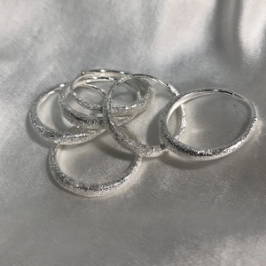 Macro detail of textured silver hoop earrings with star dust finish on silk fabric