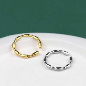 Polished gold and silver bamboo joint style open rings on a ceramic plate detail