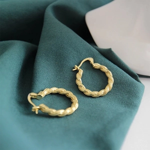 Polished S925 sterling silver gold plated twisted rope hoop earrings on green fabric