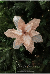 Close-up of glittered rose gold poinsettia flower on a decorated Christmas tree with lights
