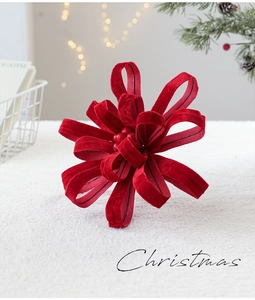 Close-up of red velvet Christmas bow decoration with berry center on white fur surface