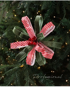 Detail of red and white striped Christmas bow with berries on a lit tree