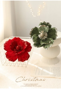 Detail of red and green velvet Christmas flowers with glitter edges and warm lights