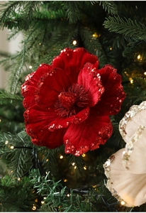 Detail of red velvet Christmas flower with sequins on a lit holiday tree branch