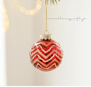Dettaglio macro di una pallina di Natale rossa con motivo a chevron dorato e glitter