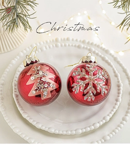 Dettaglio di palline di Natale rosse con motivi glitterati di alberi e fiocchi