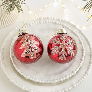 Set di due palline di Natale rosse da 8cm con motivi glitterati di fiocchi e alberi