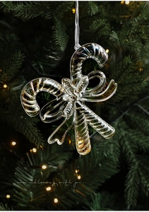 Detail of transparent iridescent candy cane ornament with bow on Christmas tree branch