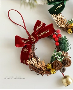 Détail d'une couronne de Noël avec nœud en velours rouge, pommes de pin, baies et cloches