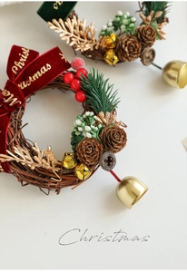 Détail de mini couronne de Noël artisanale avec nœud rouge et cloches dorées décoratives
