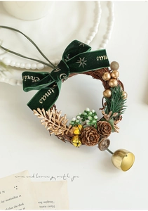 Détail de couronne de Noël avec nœud en velours vert, pommes de pin et cloche dorée