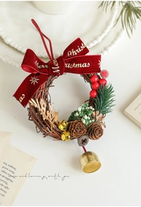 Vue détaillée de couronne de Noël avec nœud en velours rouge, pommes de pin et cloches