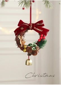 Détail d'une couronne de Noël avec nœud en velours rouge, pommes de pin et cloche dorée