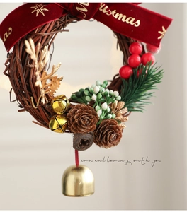 Gros plan d'une couronne de Noël avec pommes de pin, baies rouges et clochettes dorées sur vigne