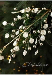 Detailed view of pearl white shells and silver baubles on a gold Christmas tree stem