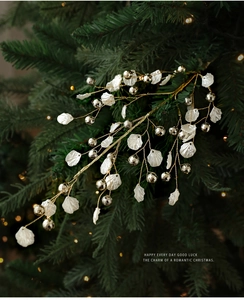 Close-up of golden Christmas branches with white flower charms and shiny bells on a tree