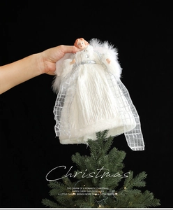 Detailed view of a white angel tree topper with feather wings being placed on a tree