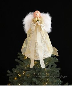 Close-up of a Christmas tree topper angel with white feather wings and gold star patterns