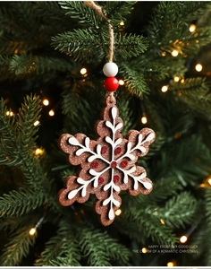 Detailed view of snowflake gingerbread ornament with red glitter on a festive Christmas tree