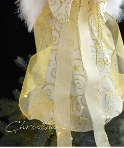 Close-up of white and gold Christmas angel tree topper with feathers and glitter details
