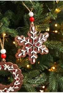 Macro detail of wooden gingerbread snowflake ornaments with red glitter on Christmas tree