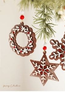 Close-up of wooden gingerbread Christmas ornaments with white cutout patterns and red beads