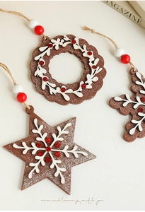 Detail of wooden gingerbread Christmas ornaments with snowflake patterns and red glitter