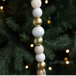 Detail von Weihnachts-Holzperlen mit Rentier-Muster und Merry Christmas Text am grünen Baum