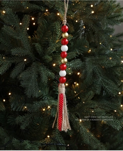 Makro-Detail von Weihnachtsperlen mit roter Schleife und Jutequaste am Tannenbaum