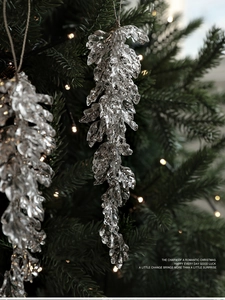 Sparkling pink pine cone acrylic ornament on Christmas tree with warm bokeh light