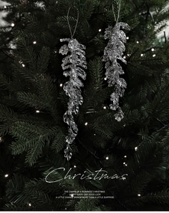 Close-up of clear acrylic Christmas icicle pendants with faceted details on a tree