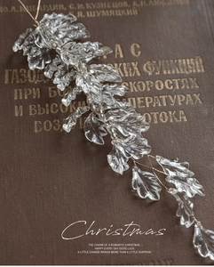 Detail of acrylic leaf ornament with white beads and gold wire on vintage books