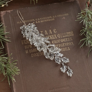 Sparkling acrylic champagne leaf ornament with glitter on vintage book with pine branches