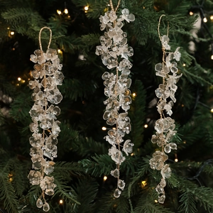 Three elegant champagne pink acrylic leaf pendants hanging on a festive Christmas tree