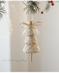 Detailopname van kerstboomhanger met witte parels en gouden lintversieringen
