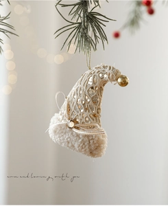 Detail van kant kerstmuts ornament met gouden lovertjes en bel aan de kerstboomtak