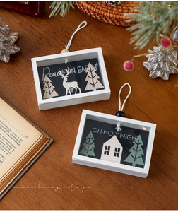 Detail view of two wooden Christmas shadow boxes with 3D reindeer and tree on rustic desk